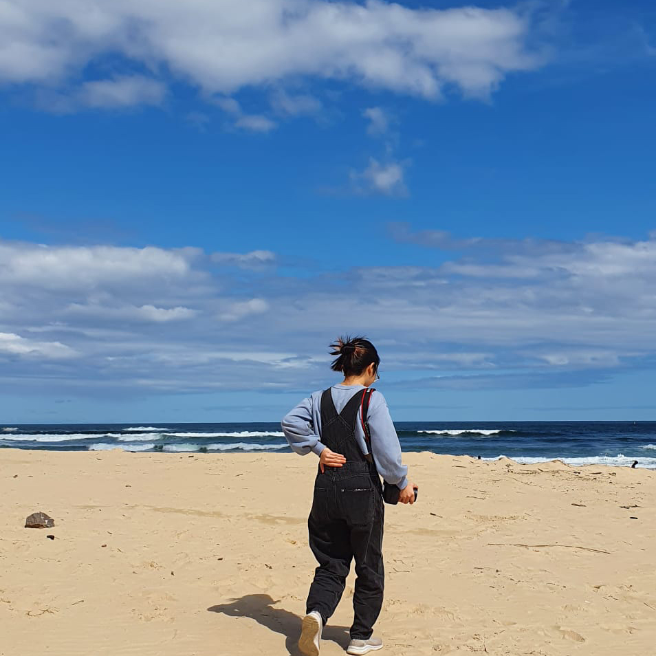 A person walking on a beach on a bright sunny day.